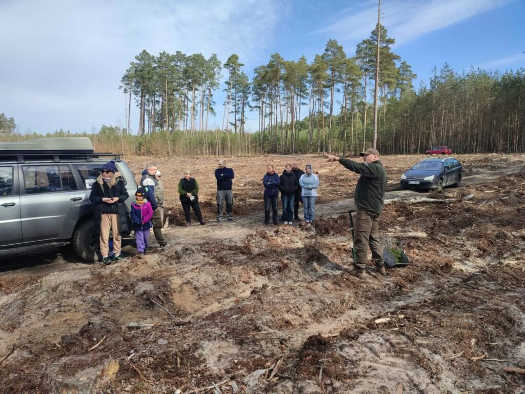 Fotografia przedstawia grupę osób na tle lasu.