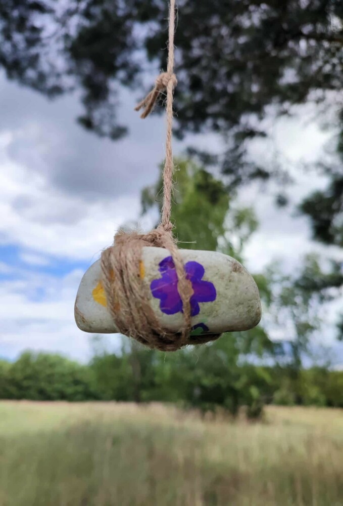Fotografia przedstawia zawieszony na sznurku kolorowy kamień.