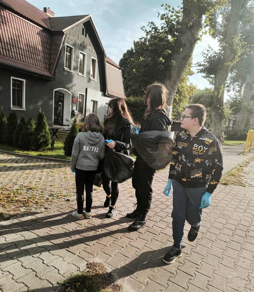 Fotografia przedstawia grupę osób z workami na śmieci.