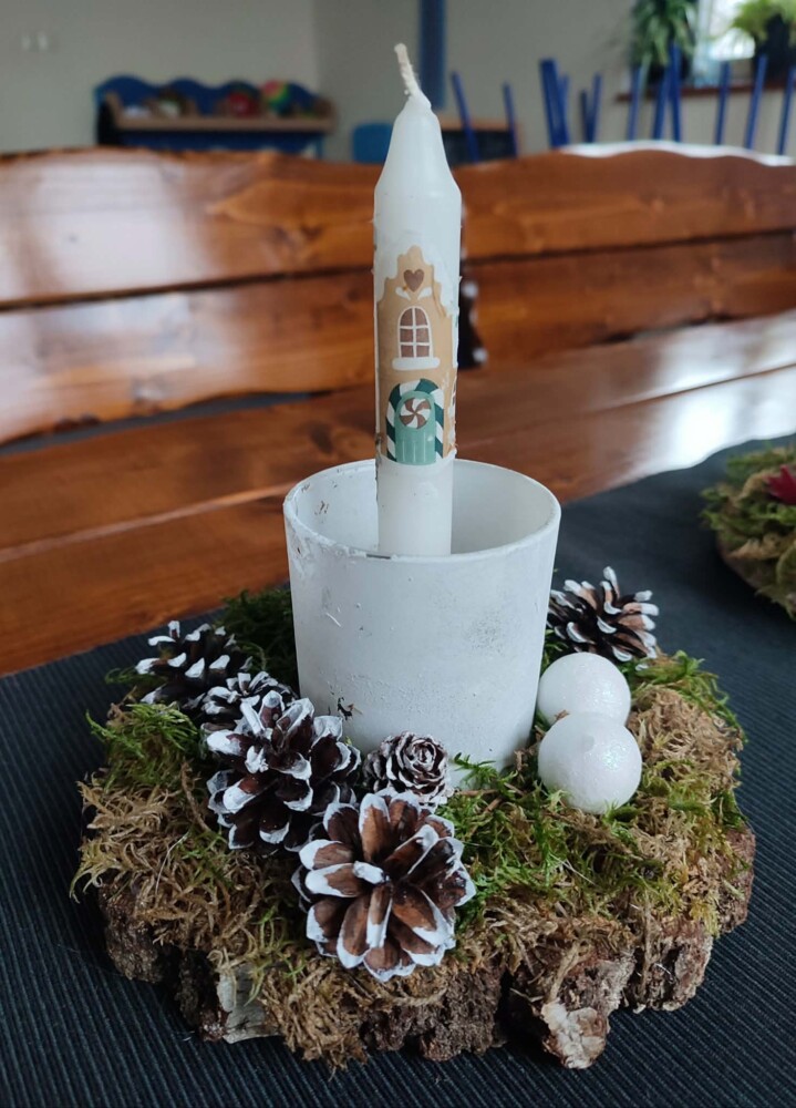 Fotografia przedstawia stroik bożonarodzeniowy ze świeczką.