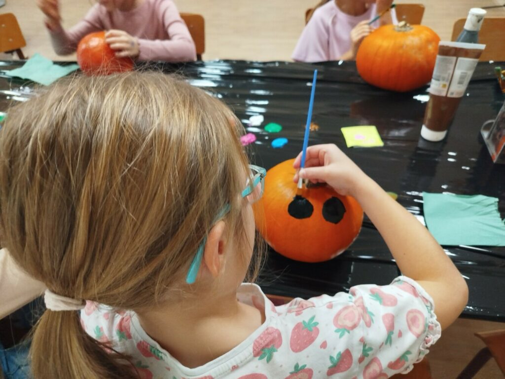 Dziewczynka malująca dyni czarne oczka.