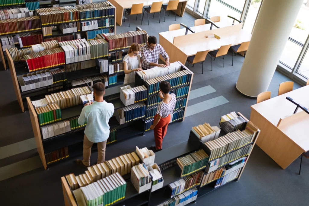 4 osoby szukają książek w bibliotece