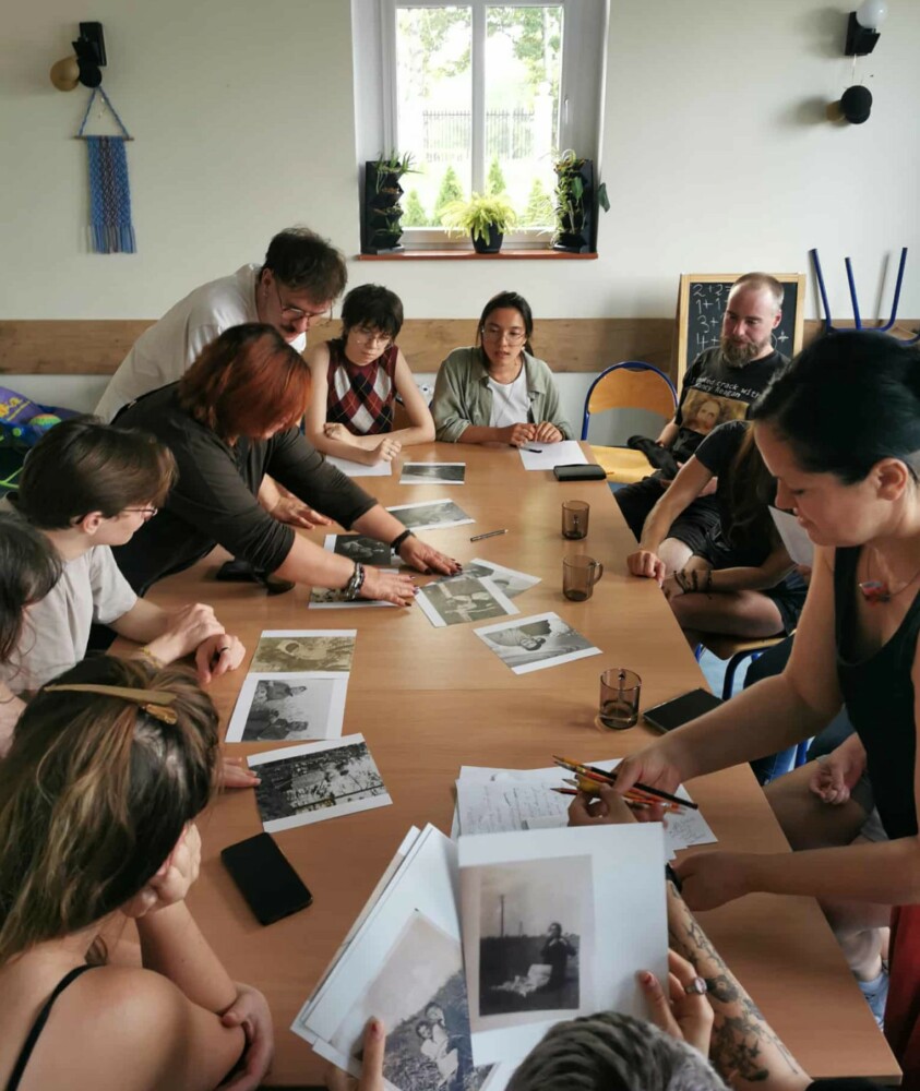 Zdjęcie przedstawia grupę osób oglądających stare fotografie.