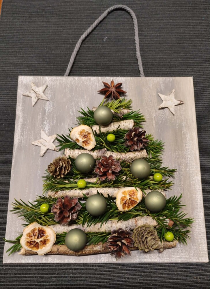 Fotografia przedstawia obrazek, na którym jest choineczka z gałązek i mchu.